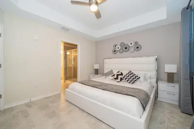 a white bedroom with a white bed and a ceiling fan at 3150-308BR STOREY LAKE, CONDO 3/2 POOL VIEW in Kissimmee