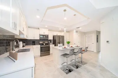 a kitchen with white cabinets and a island with bar stools at 3180-201JB STOREY LAKE, CONDO 3/2 GARDEN VIEW in Kissimmee