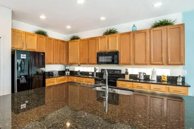a kitchen with wooden cabinets and a black refrigerator at Stunning LAKE VIEW, Big Pool Area with CDC Standards #6BV507 in Kissimmee