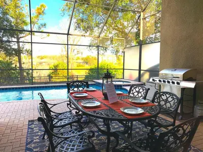 a patio with a table and chairs and a pool at Ohana House at Windsor Hills, Disney World Luxury Rental in Orlando