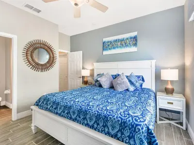 a bedroom with a bed with a blue comforter and a mirror at Ohana House at Windsor Hills, Disney World Luxury Rental in Orlando