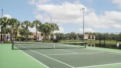 a tennis court with a net on top of it at Spacious Vacation Home with Pool & Jacuzzi Near Disney in Kissimmee