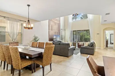 a dining room and living room with a table and chairs at Spacious Vacation Home with Pool & Jacuzzi Near Disney in Kissimmee