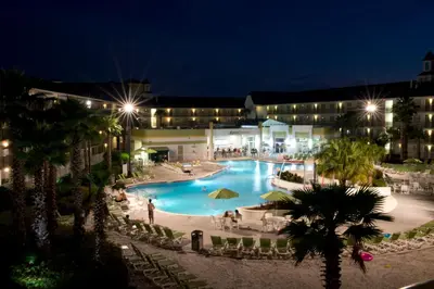a large swimming pool at night with people standing around it at Avanti International Resort in Orlando
