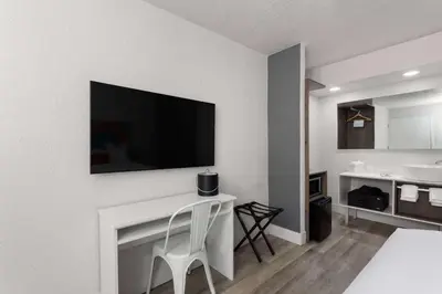 a living room with a white table and a television on a wall at Travelodge by Wyndham Orlando Lake Buena Vista South in Kissimmee
