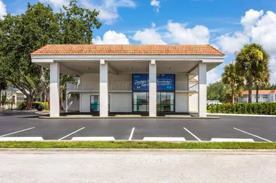 a parking lot in front of a building at Travelodge by Wyndham Orlando Lake Buena Vista South in Kissimmee