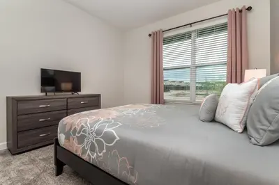 a bedroom with a bed and a television and a window at Villa wPrivate Pool &Themed Rooms, near Disney in Kissimmee