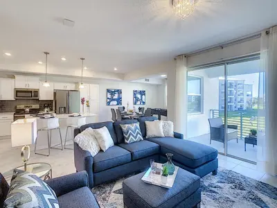 a living room with a blue couch and a kitchen at Updated Condo, 5 mi to Disney, On-site Water Park in Kissimmee