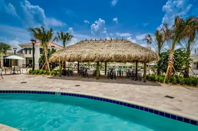 a resort with a large pool with chairs and a straw umbrella at Modern Condo near Disney Foosball Water Park in Kissimmee
