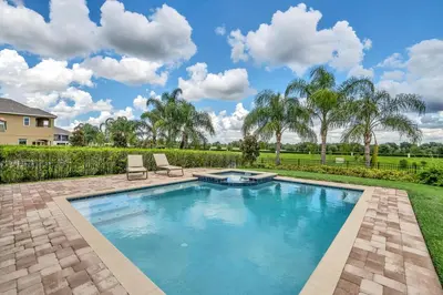 a swimming pool with two chairs in a yard at Modern Villa wPrivate Pool and Air Hockey Table in Orlando