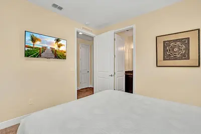 a white bedroom with a bed and a painting on the wall at Modern Villa wPrivate Pool and Air Hockey Table in Orlando