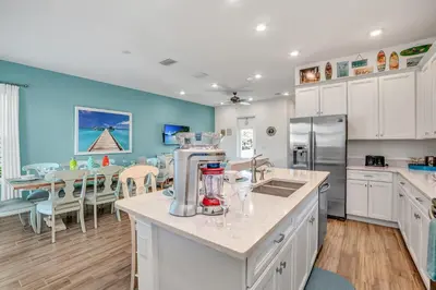 a kitchen with white cabinets and a dining room with a table at Large Margaritaville Villa w PRIVATE POOL View in Orlando
