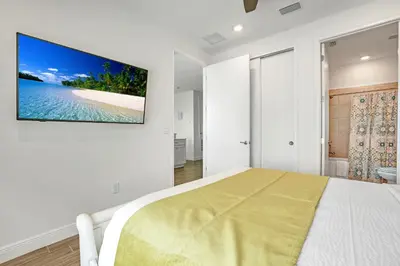 a white bedroom with a tv hanging on the wall at Large Margaritaville Villa w PRIVATE POOL View in Orlando