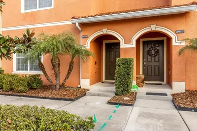 a house with a door and palm trees in front of it at Spetacular TownHome With Private Pool close to Disney 8919PP in Kissimmee