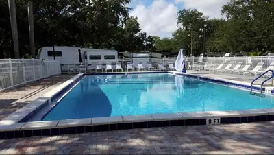 a large swimming pool with chairs and an rv at Cozy Tiny Home Near Disney World & Orlando Parks! in Kissimmee