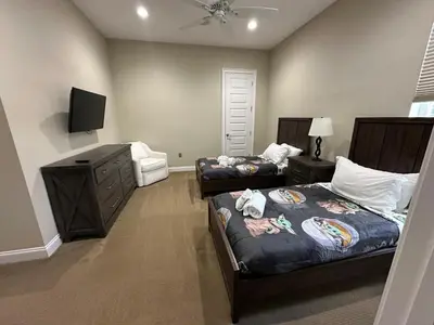 a bedroom with two beds and a dresser and a tv at Mickeys Atlantis - Luxury 8BR Mansion Oasis Pool Hot Tub Outdoor Kitchen Home Theater, Game Room & More! 2 Miles to Disney in Orlando