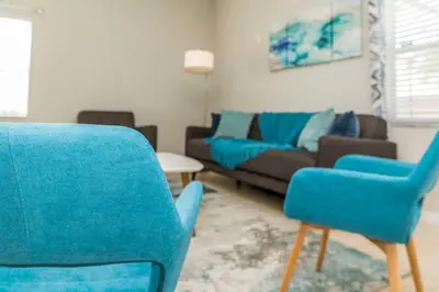 a living room with blue chairs and a couch at Roomy Town Home, Mickey-Themed Bedroom! #4BV550 in Kissimmee