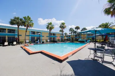 a swimming pool with tables and umbrellas in a resort at Garnet Inn & Suites, Orlando in Orlando
