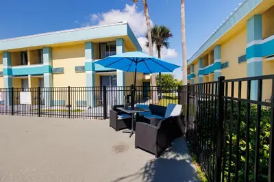 a table and chairs with an umbrella in front of a building at Garnet Inn & Suites, Orlando in Orlando