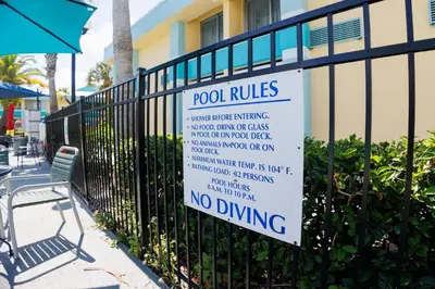 a sign on a fence that says pool rules at Garnet Inn & Suites, Orlando in Orlando