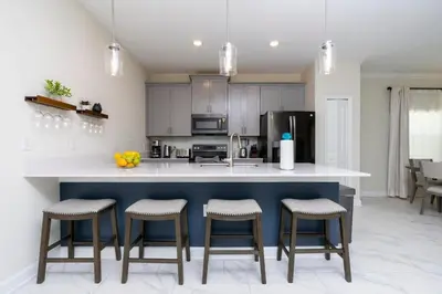 a kitchen with a white counter and stools in it at Stunning 5 Bd w/ Pool Close to Disney 2905 in Kissimmee
