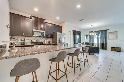 a kitchen with a bar with stools in a room at 7 Mi Walt Disney World! Family Gem with Private Pool in Kissimmee