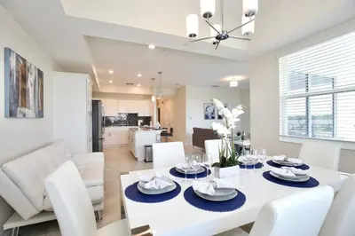 a dining room and living room with a white table and chairs at Amazing apartment in lux resort Storey Lake with great amenities 10 miles to Disney! in Kissimmee