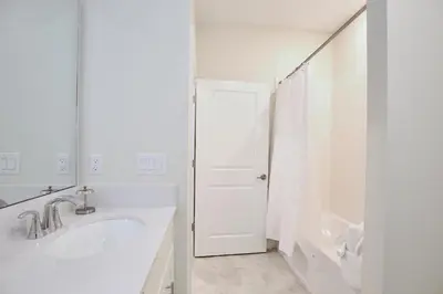 a white bathroom with a sink and a shower at Amazing apartment in lux resort Storey Lake with great amenities 10 miles to Disney! in Kissimmee