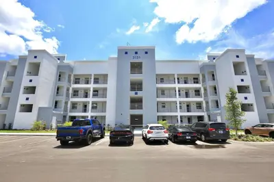 a large white building with cars parked in a parking lot at Amazing apartment in lux resort Storey Lake with great amenities 10 miles to Disney! in Kissimmee