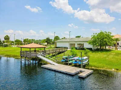 a house with a dock and boats on the water at Amazing apartment in lux resort Storey Lake with great amenities 10 miles to Disney! in Kissimmee