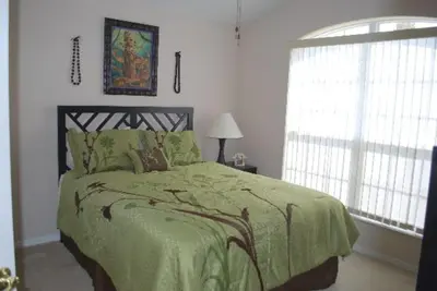 a bedroom with a green bed and a window at Luxury 5-Bed Villa, located only 3 miles from Disney World in Kissimmee