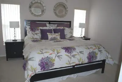 a bedroom with a large bed with purple flowers on it at Luxury 5-Bed Villa, located only 3 miles from Disney World in Kissimmee