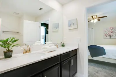 a bathroom with a sink and a large mirror at 9 Bed Storey Lake Resort Game Room Pool home in Kissimmee