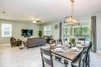 a dining room and living room with a table and chairs at 9 Bed Storey Lake Resort Game Room Pool home in Kissimmee