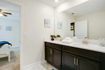 a bathroom with a sink and a large mirror at 9 Bed Storey Lake Resort Game Room Pool home in Kissimmee