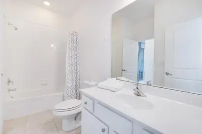 a white bathroom with a toilet and a tub and a sink at 5 Bed 5 Bath in 5 Star Resort Near Disney! home in Kissimmee