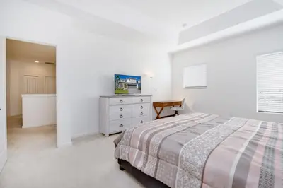 a white bedroom with a bed and a dresser at 5 Bed 5 Bath in 5 Star Resort Near Disney! home in Kissimmee
