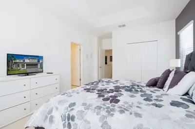 a white bedroom with a bed and a tv at 5 Bed 5 Bath in 5 Star Resort Near Disney! home in Kissimmee