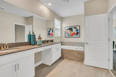 a bathroom with white cabinets and a tub and a sink at Boutique Style Home Near Disney! home in Kissimmee