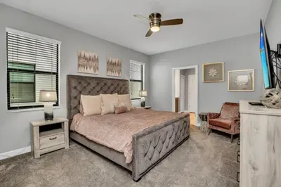 a bedroom with a large bed and a chair at Storey Lake Resort 9 Bed Game Theater Room home in Kissimmee