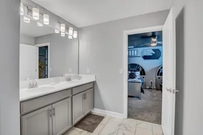 a bathroom with two sinks and a large mirror at Storey Lake Resort 9 Bed Game Theater Room home in Kissimmee