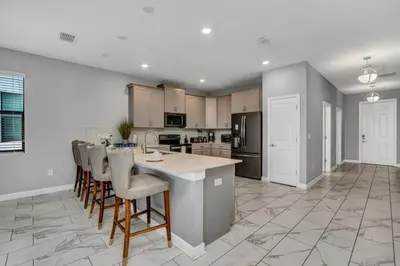 a kitchen with a large island with bar stools at Storey Lake Resort 9 Bed Game Theater Room home in Kissimmee