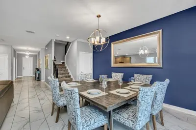 a dining room with a wooden table and blue walls at Storey Lake Resort 9 Bed Game Theater Room home in Kissimmee