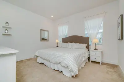 a white bedroom with a large bed and two lamps at Beautiful Home Near Disney with Private Pool! villa in Orlando