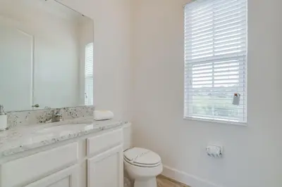 a white bathroom with a toilet and a sink at Beautiful Home Near Disney with Private Pool! villa in Orlando