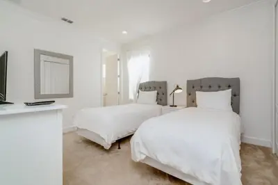 a white bedroom with two beds and a television at Beautiful Home Near Disney with Private Pool! villa in Orlando