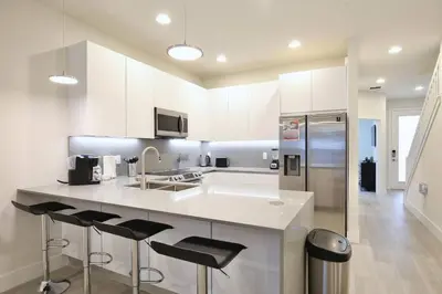 a kitchen with white cabinets and a counter with bar stools at Amazing 3 bedroomloft townhouse in Hidden Forest, with private pool! in Orlando