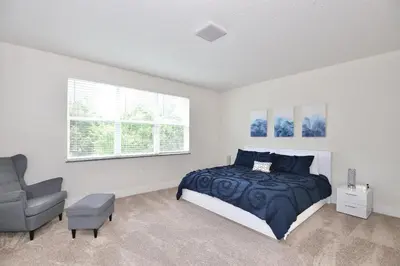 a bedroom with a bed and a chair in it at High luxury 3 bedroomloft townhouse in Hidden Forest, with private pool! in Orlando