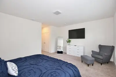 a bedroom with a bed and a chair and a television at High luxury 3 bedroomloft townhouse in Hidden Forest, with private pool! in Orlando