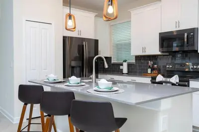 a kitchen with white cabinets and a counter with chairs at Gorgeous 5BDR Family with Pool at Storey Lake 2767 O in Kissimmee